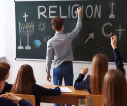 Schüler schreibt RELIGION an eine Tafel