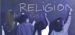 Kinder schreiben RELIGION an eine Tafel